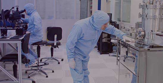 Two people in protective lab coats using lab equipment