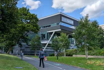 Black glass building with trees in the landscape.
