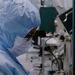Person in a lab wearing a face mask and lab protective clothing that covers the head.