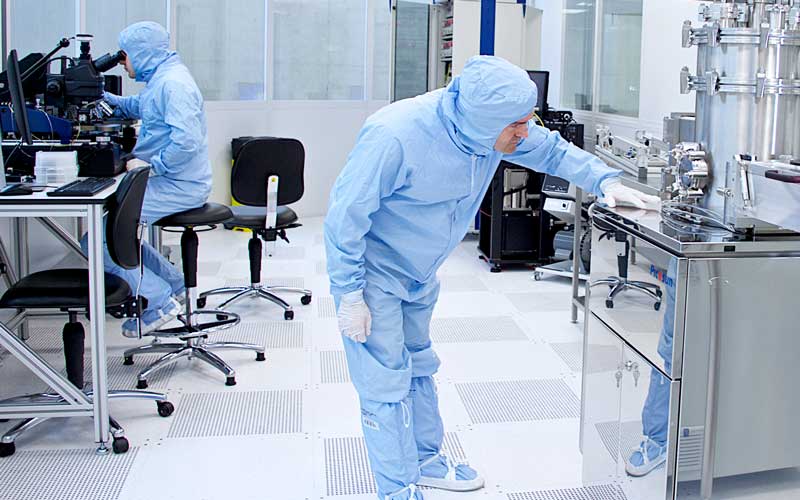 Two people in protective lab coats using lab equipment