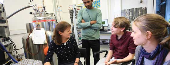 Three students looking and listening to professor